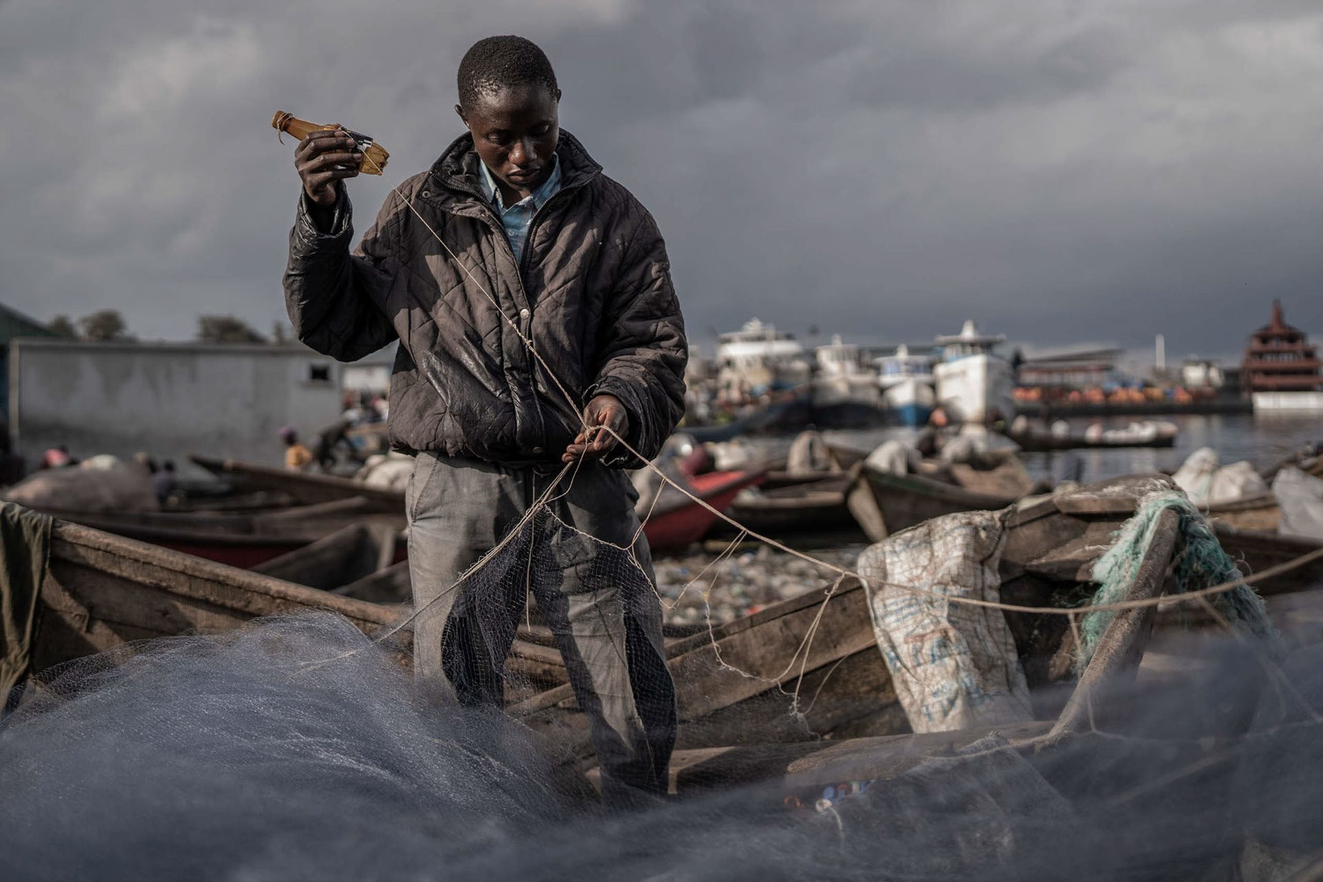 A young fisherman sorts through his nets on the shore of Lake Kivu, in Goma, DRC.